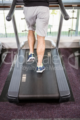 Lower section of fit man running on treadmill
