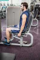 Focused man using weights machine for legs