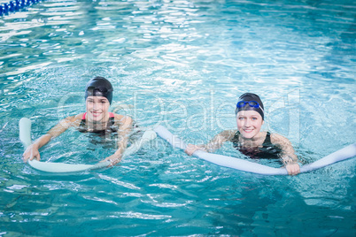 Smiling women in the pool with foam rollers