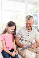 Smiling grandfather and granddaughter using tablet