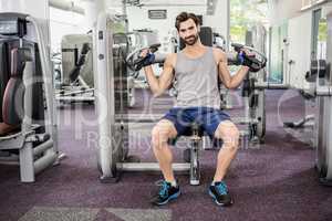 Focused man using weights machine for arms