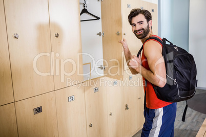 Smiling man opening locker