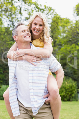 Happy husband giving piggy back to his wife