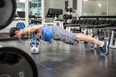 Muscular man doing push ups with kettlebells