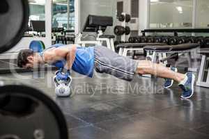 Muscular man doing push ups with kettlebells