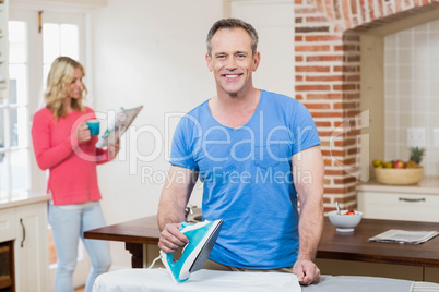 Man ironing while wife reading the news Man ironing while wife reading the news