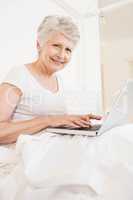 Mature woman using laptop and smiling at the camera