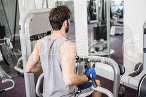 Focused man using weights machine for arms