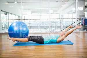 Fit blonde on mat holding fitness ball with legs