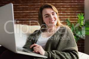 Pretty woman using laptop lying on the couch