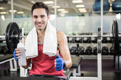 Smiling man showing thumb up and holding bottle of water