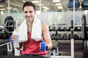 Smiling man showing thumb up and holding bottle of water