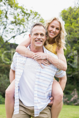 Happy husband giving piggy back to his wife