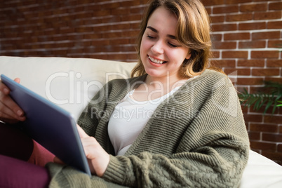 Pretty woman using tablet lying on the couch