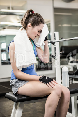 Tired brunette on bench wiping sweat with towel