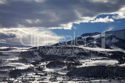 Winter mountains and village at evening