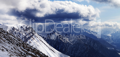 Panoramic view on winter mountains in evening and cloudy sky