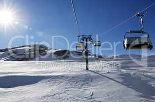 Chair-lift and blue sky with sun