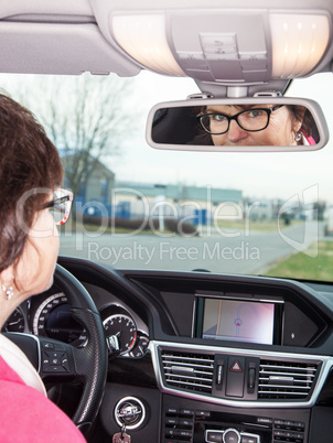 Woman looks in the rearview mirror of her car