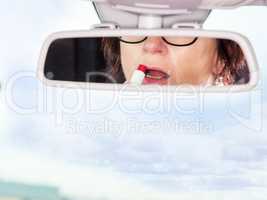 Woman looks in the rearview mirror of her car