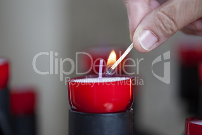 Female mature woman burning candle light in church