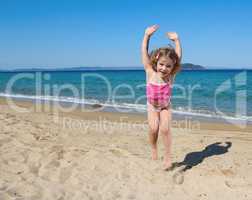 happy little girl jumping on the beach