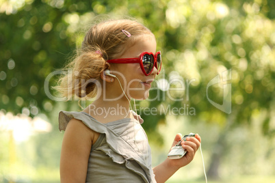 beauty little girl listening music in park