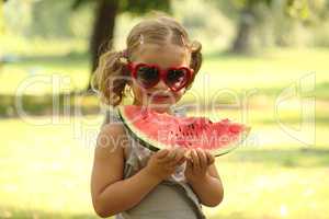 little girl with sunglasses eat watermelon