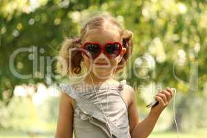 little girl with sunglasses listening music