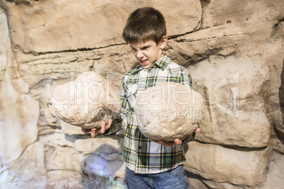 Strong child holds heavy stone