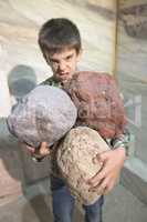 Strong child holds heavy stones