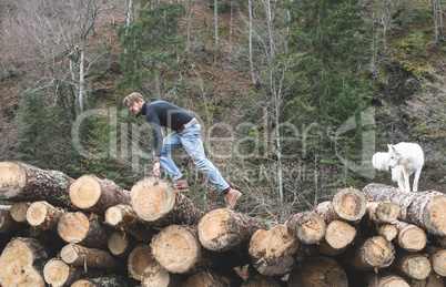 Young man and dog on logs in the forest