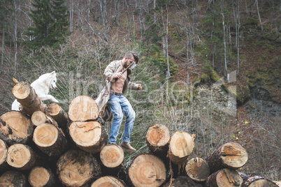 Young man and dog on logs in the forest