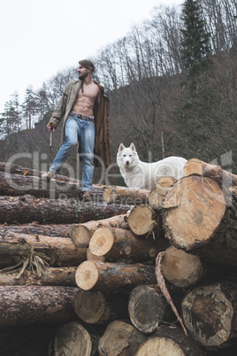 Young man and dog on logs in the forest