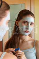 girl with cosmetic mask looking into a mirror
