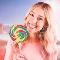 Composite image of a beautiful woman holding a giant lollipop