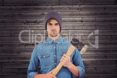 Composite image of portrait of serious hipster holding axe