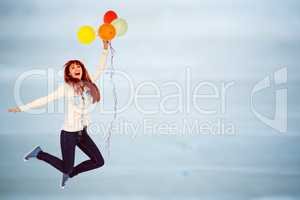 Composite image of smiling hipster woman holding balloons