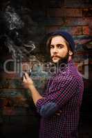 Composite image of side view of hipster holding smoking pipe
