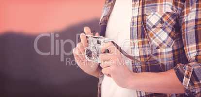 Composite image of mid section of hipster holding camera