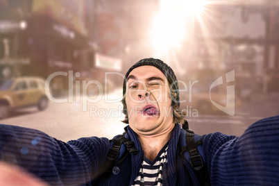 Composite image of hipster holding camera and grimacing