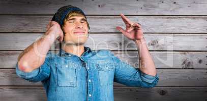 Composite image of cheerful hipster listening to music