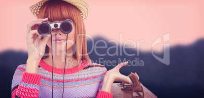 Composite image of smiling hipster woman looking through binocul