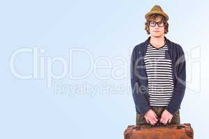 Composite image of serious hipster holding a suitcase