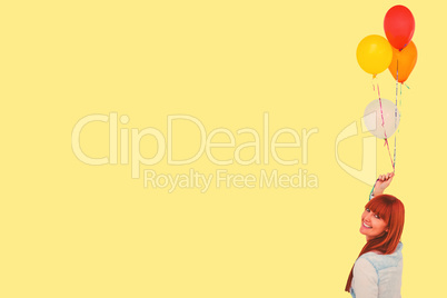 Composite image of smiling hipster woman holding balloons