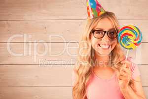 Composite image of portrait of a hipster with a party hat holdin