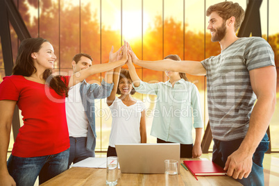 Composite image of happy business team putting their hands toget