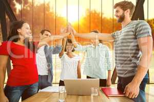 Composite image of happy business team putting their hands toget