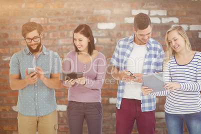 Composite image of smiling business people using electronic gadg