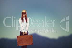 Composite image of portrait of a hipster woman holding suitcase